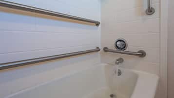 A bathtub with two metal grab bars, a faucet, and a drain.