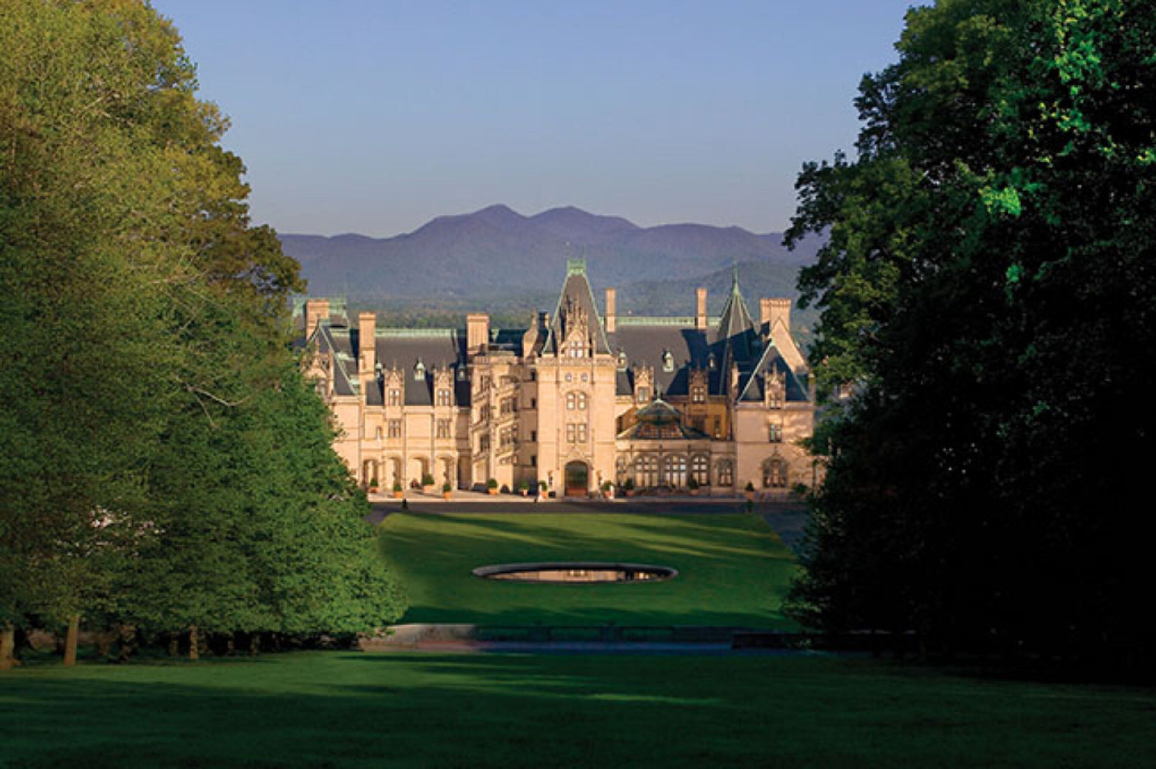 A large, historic building with multiple towers and a well-maintained lawn.