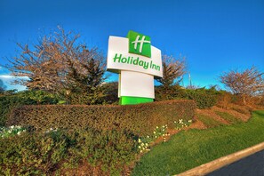 A Holiday Inn sign with a green and white logo, surrounded by well-maintained hedges and trees. - Holiday Inn Asheville Biltmore by IHG (Asheville)