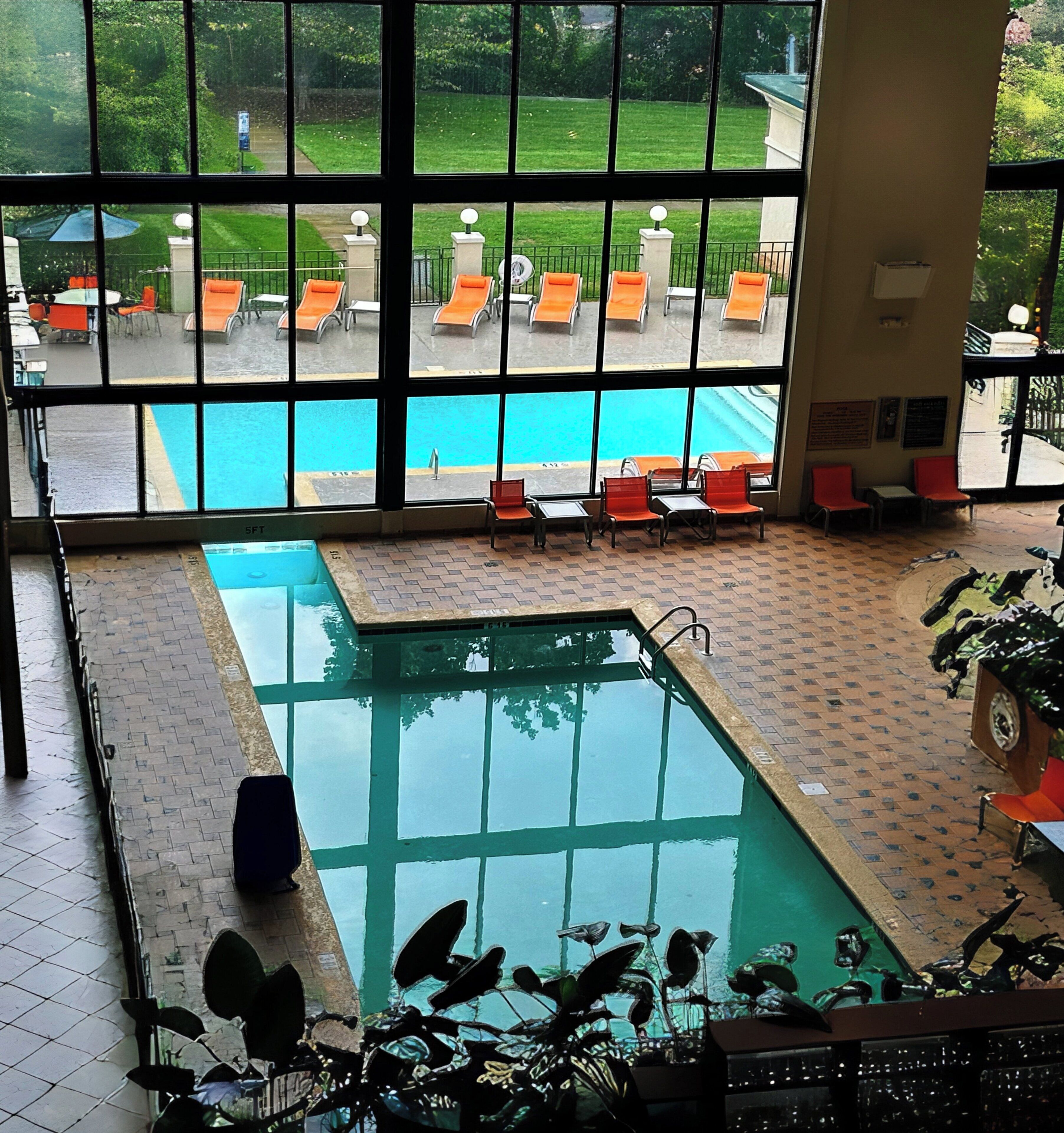 Una piscina interior con varias pistas, sillas de descanso y vistas al exterior a través de amplios ventanales.
