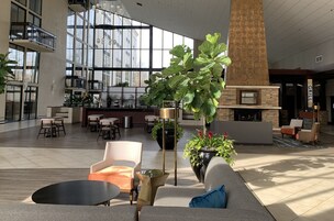 A spacious lobby with modern furniture, large windows, and a fireplace.