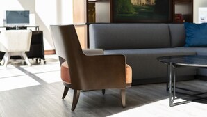 A modern living room with a grey sofa, a brown armchair, and a round coffee table. - Holiday Inn Asheville Biltmore by IHG (Asheville)