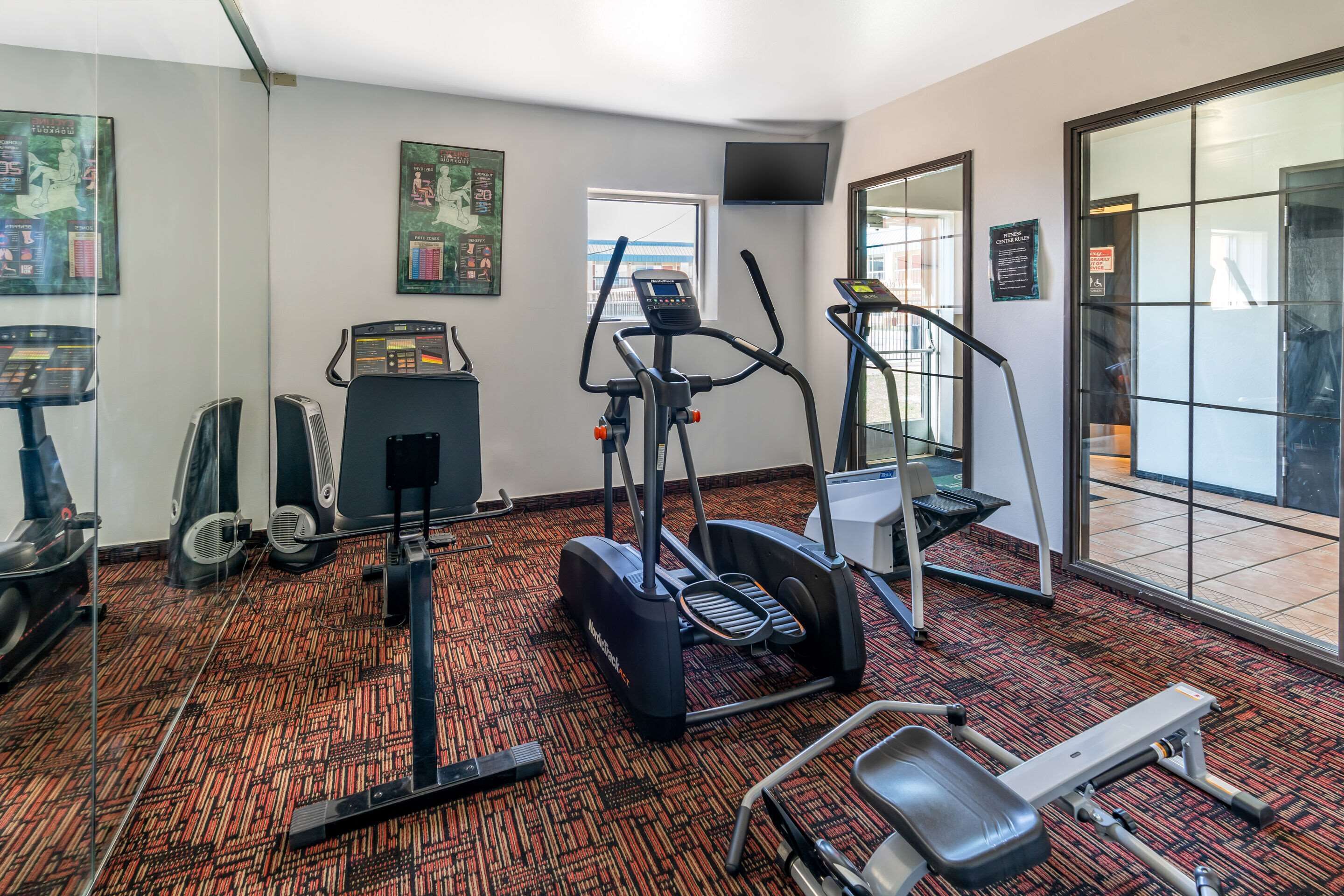 Ein Fitnessstudio mit Laufbändern, Crosstrainern und Fahrrädern.
