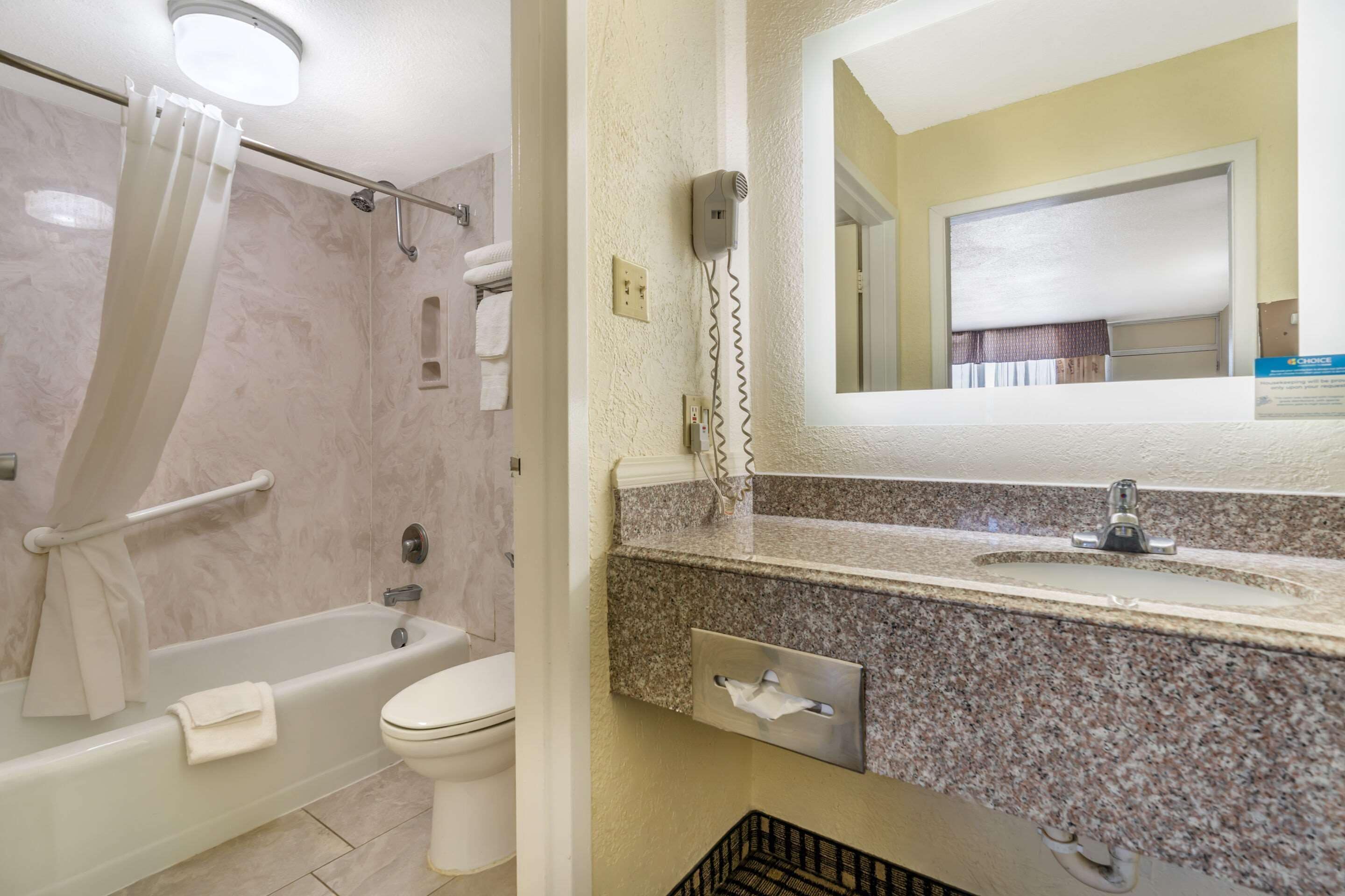 A bathroom with a bathtub, toilet, and a vanity with a mirror.