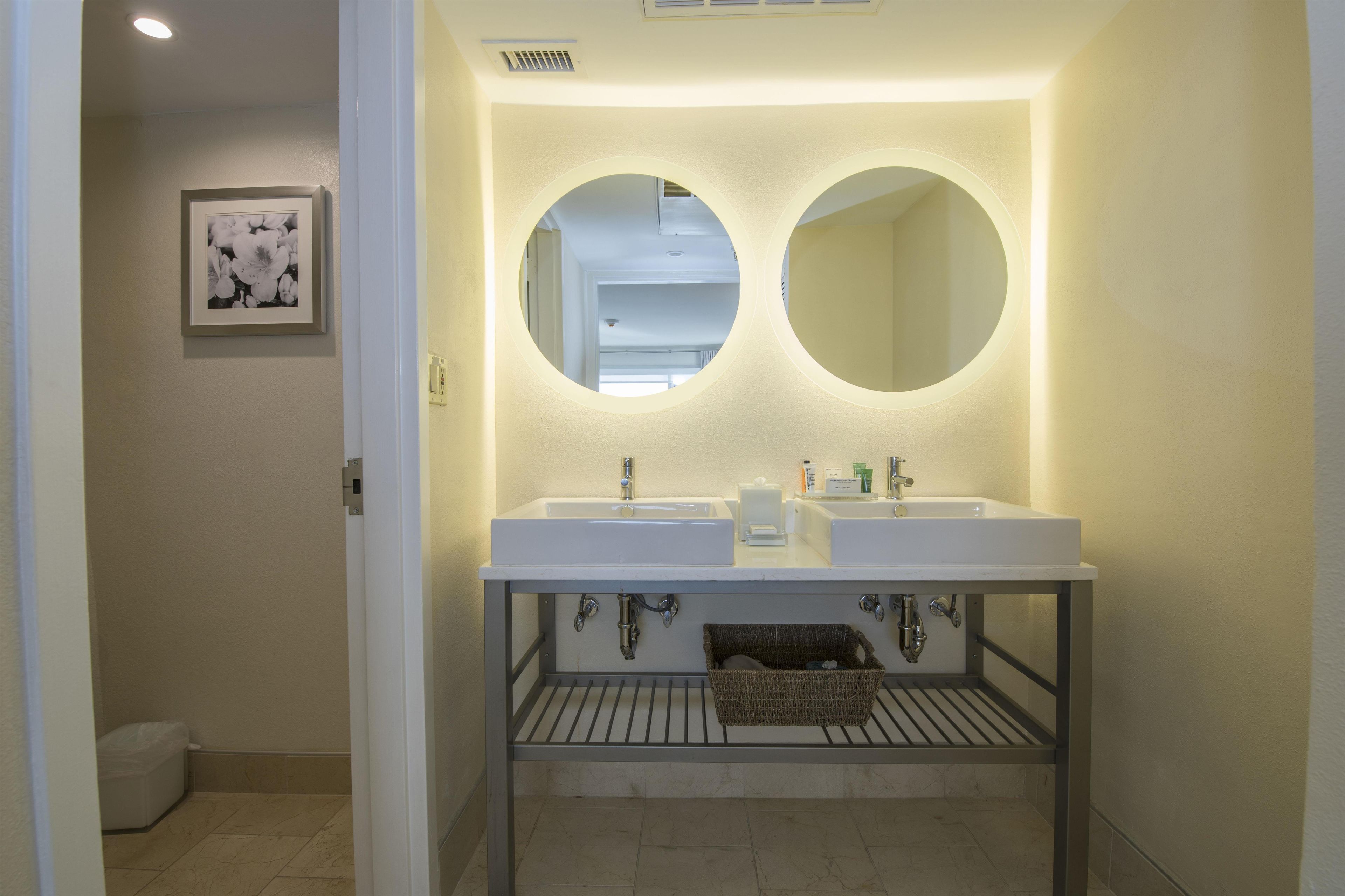 Un baño con dos lavamanos, un espejo y un perchero para toallas.