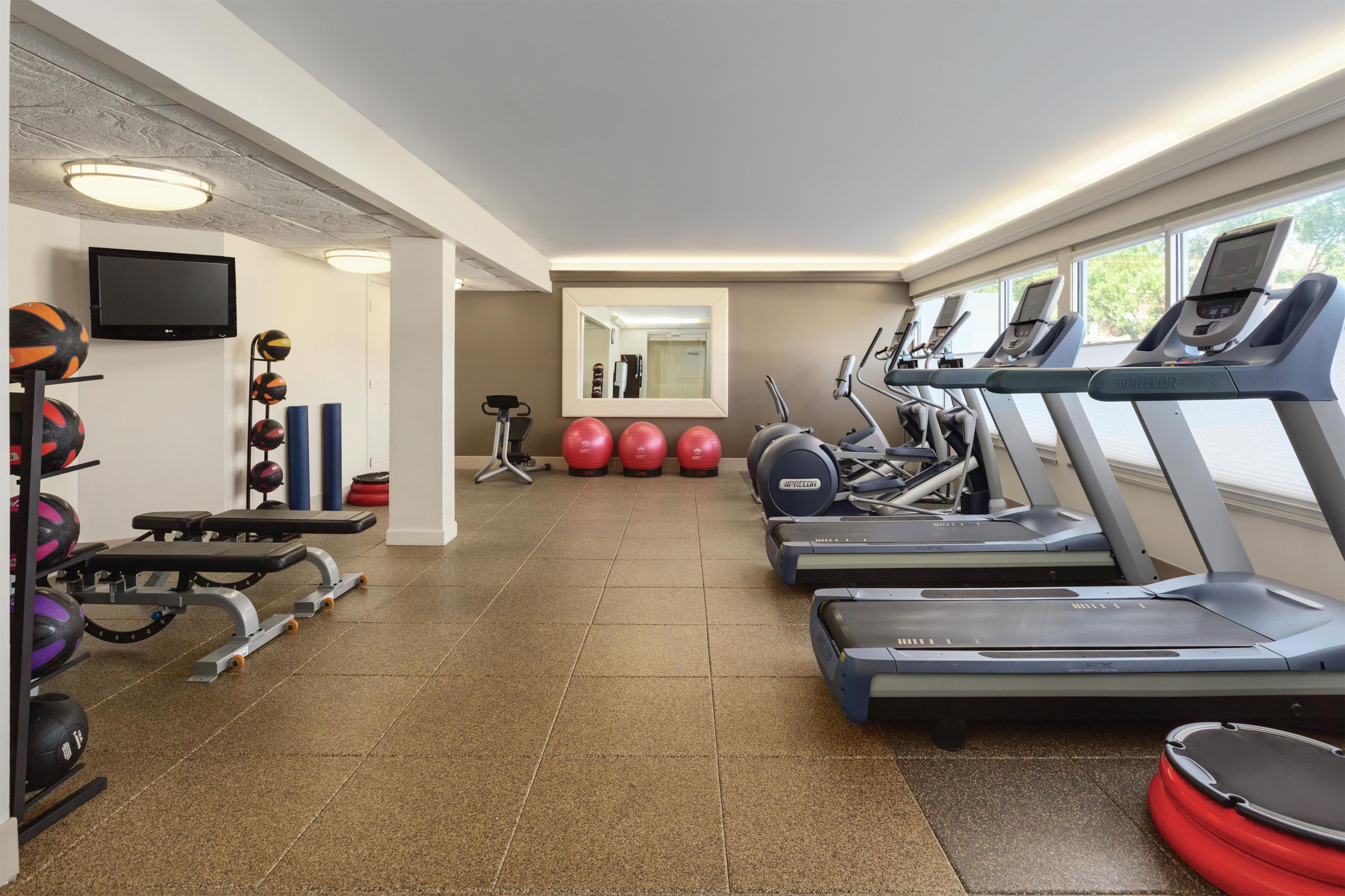 Een sportschool met loopbanden, fitnessballen en gewichttoestellen.