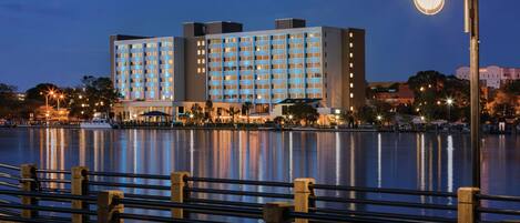 A waterfront hotel with multiple floors, a dock, and a reflection in the water.