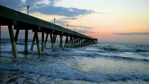 Un muelle que se adentra en el mar, con un atardecer de fondo.