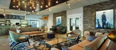 A modern lounge area with sofas, armchairs, and a coffee bar.