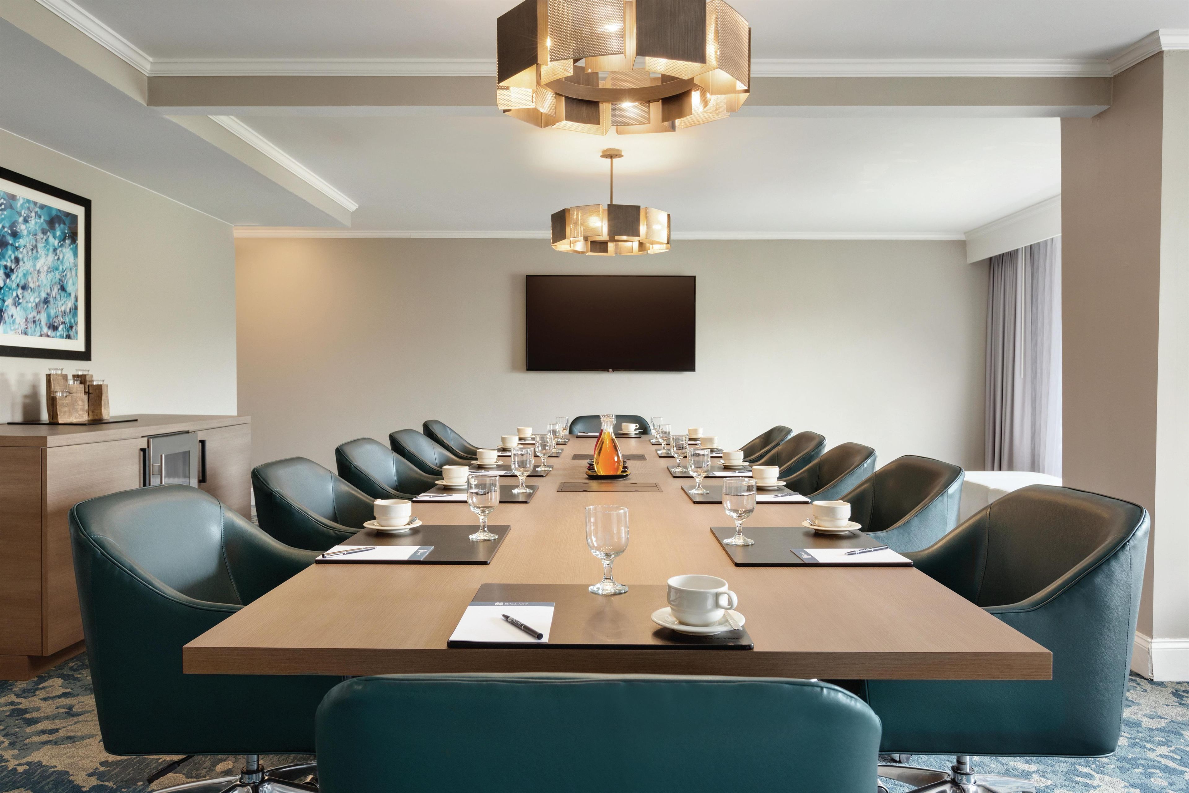 Une salle de conférence dotée d’une longue table, de nombreuses chaises et d’un lustre moderne.