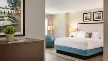 A hotel room with a bed, bedside table, lamp, and a framed picture on the wall.