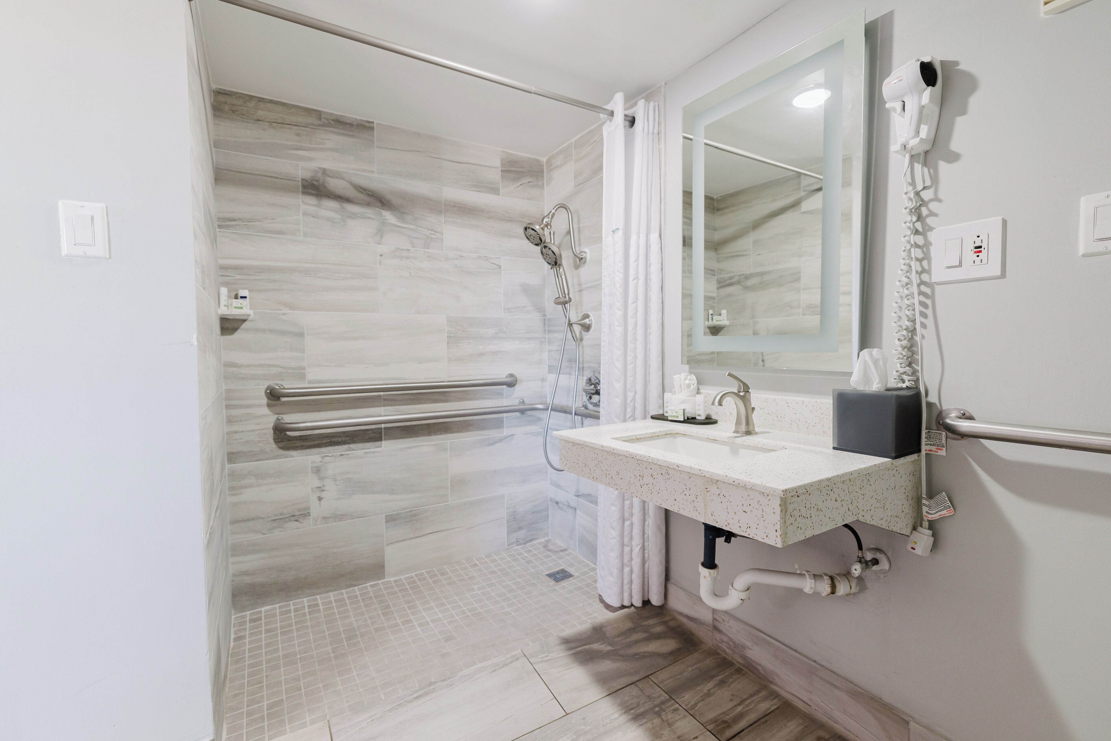 A modern bathroom with a shower, a sink, and a mirror.