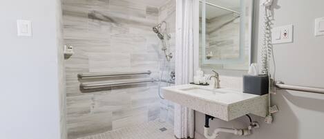 A modern bathroom with a shower, a sink, and a mirror.