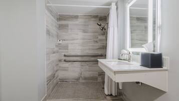 A modern bathroom with a shower, a sink, and a large mirror.