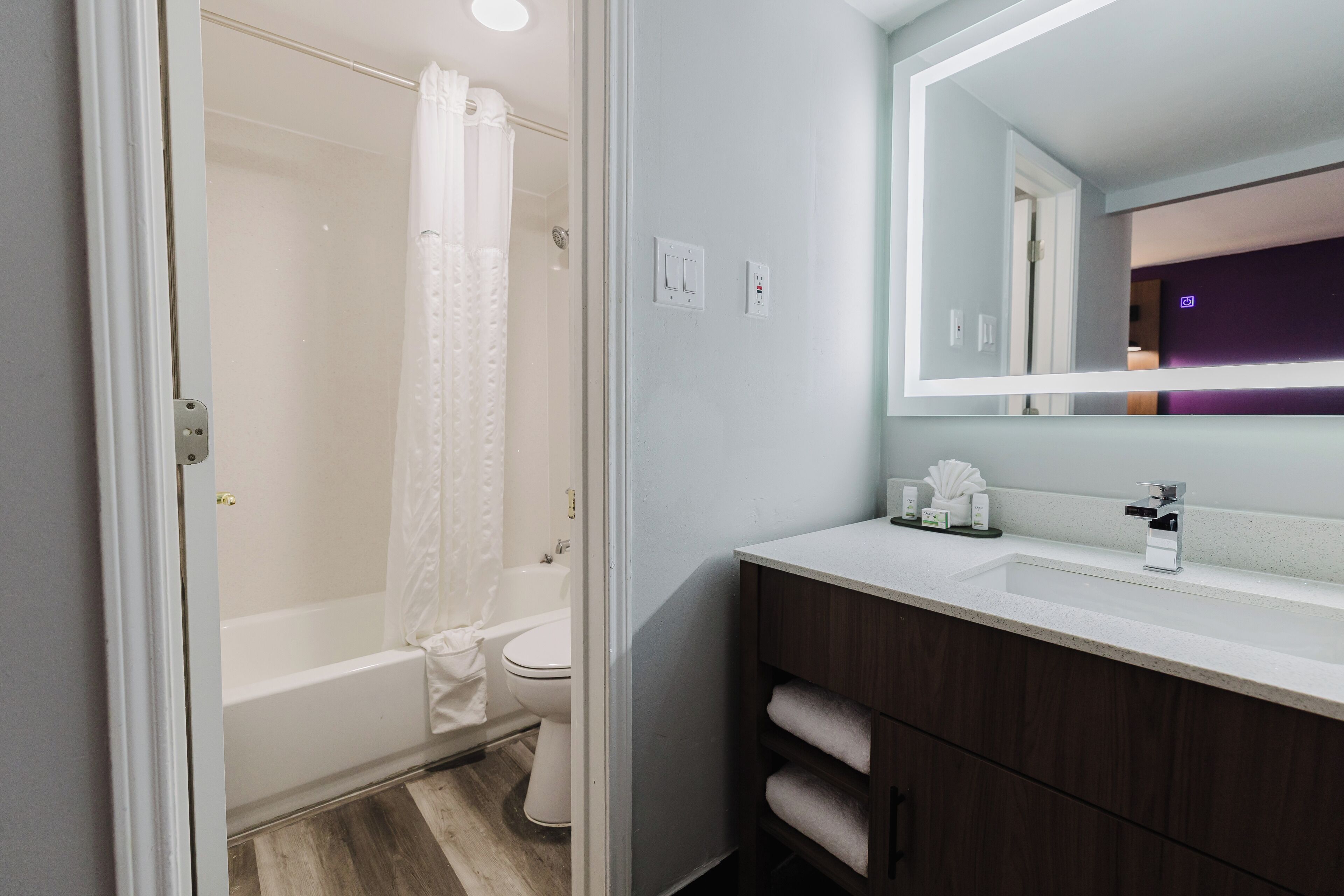 A modern bathroom with a bathtub, toilet, and vanity with a mirror.