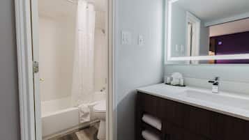 A modern bathroom with a bathtub, toilet, and vanity with a mirror.