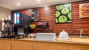 A hotel reception area with a coffee machine, a fruit display, and a La Quinta sign. - La Quinta Inn by Wyndham Amarillo Mid-City (Amarillo)