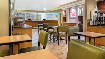 Un restaurante con mesas y sillas de madera, una barra con una máquina de café y una pared decorativa.
