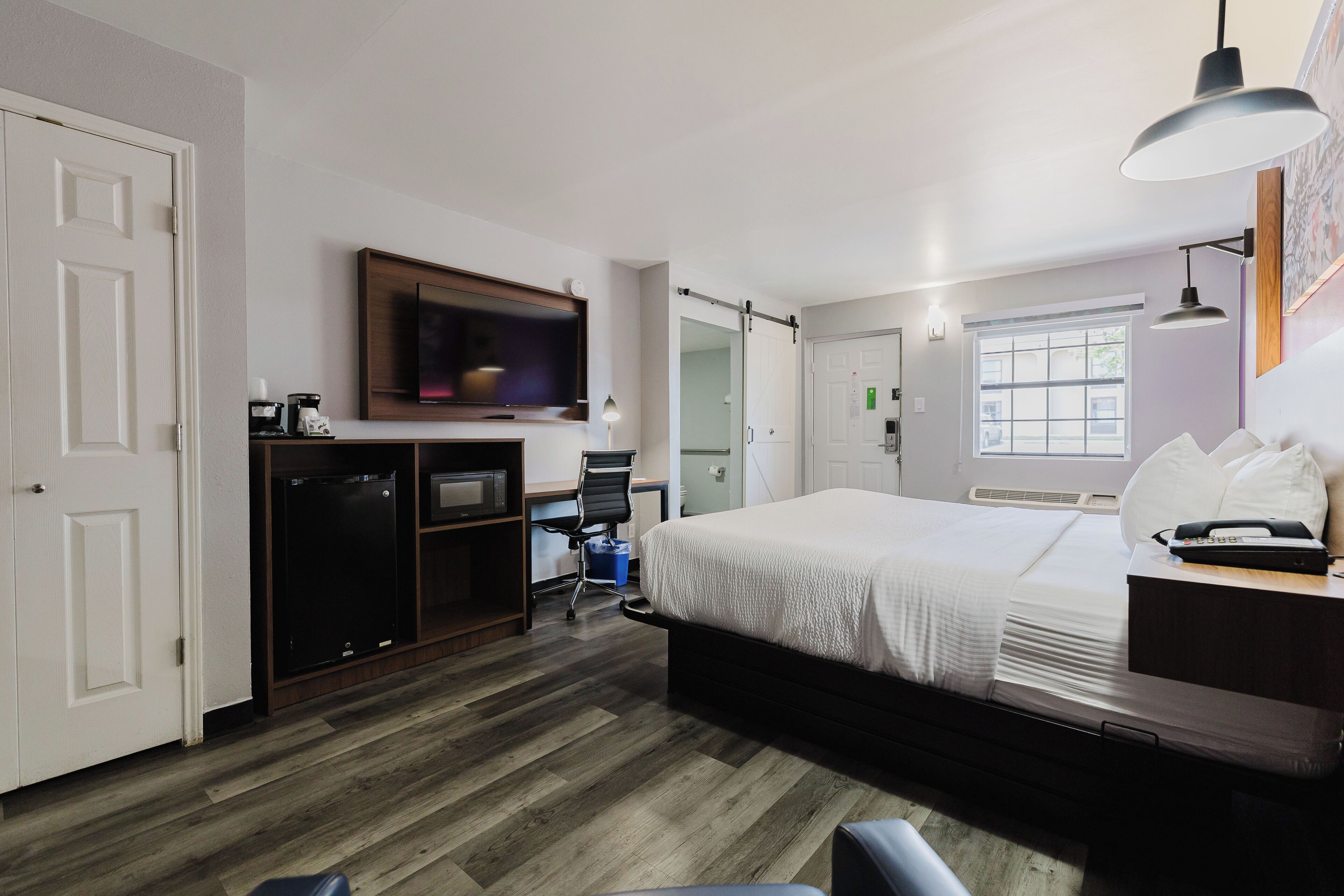 A hotel room with a bed, a desk, a TV, a chair, and a wardrobe.