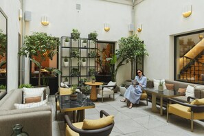 A modern outdoor seating area with multiple tables and chairs, surrounded by potted plants and a staircase. - Asturias (Madrid)