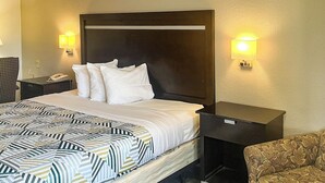 Een hotelkamer met een groot bed, een hoofdeinde, twee nachtkastjes, een telefoon en twee wandlampen.