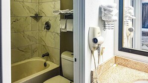 Een badkamer met een bad, toilet en een haardroger bevestigd aan de muur.