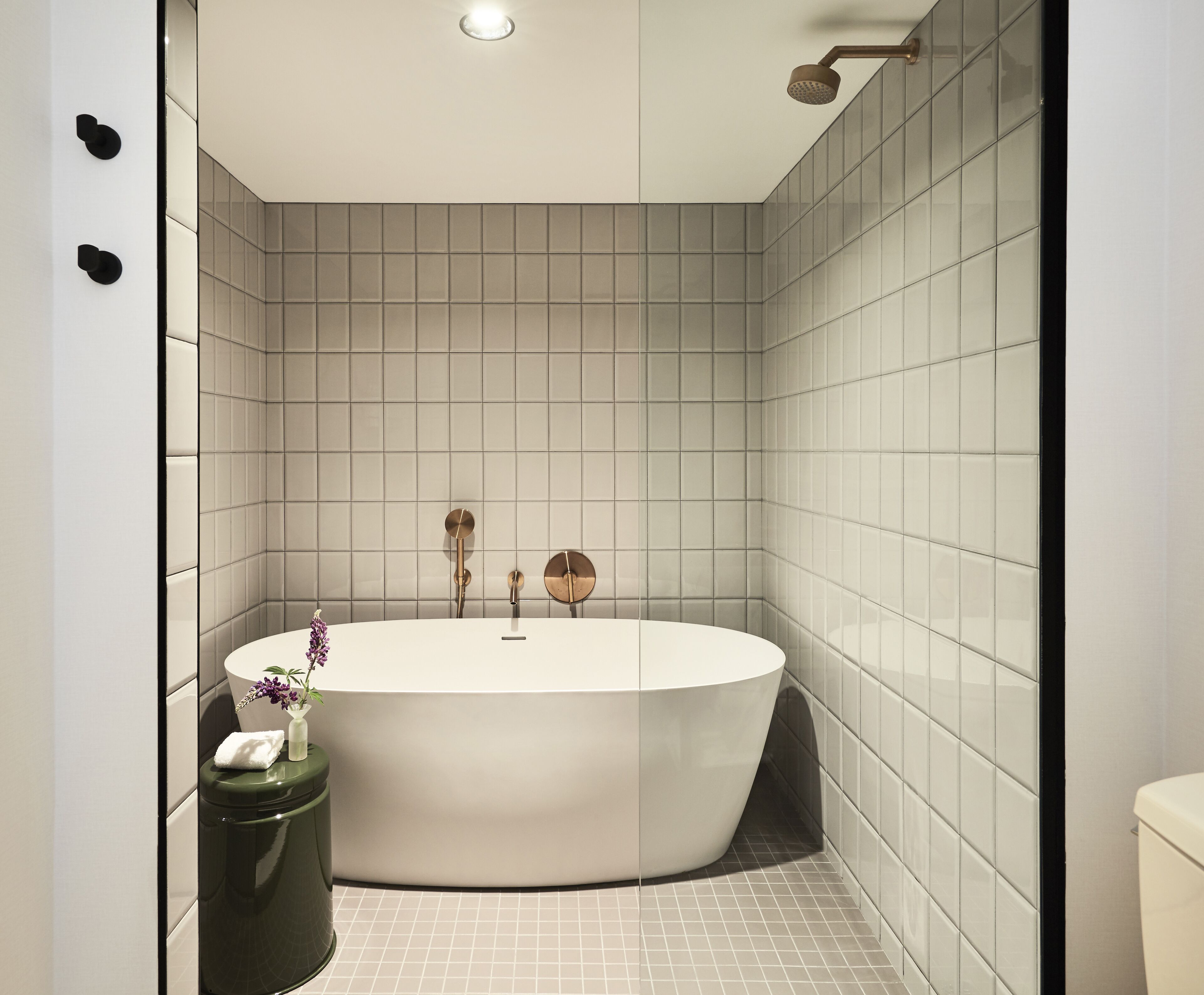A modern bathroom with a freestanding bathtub, a toilet, and a trash can.