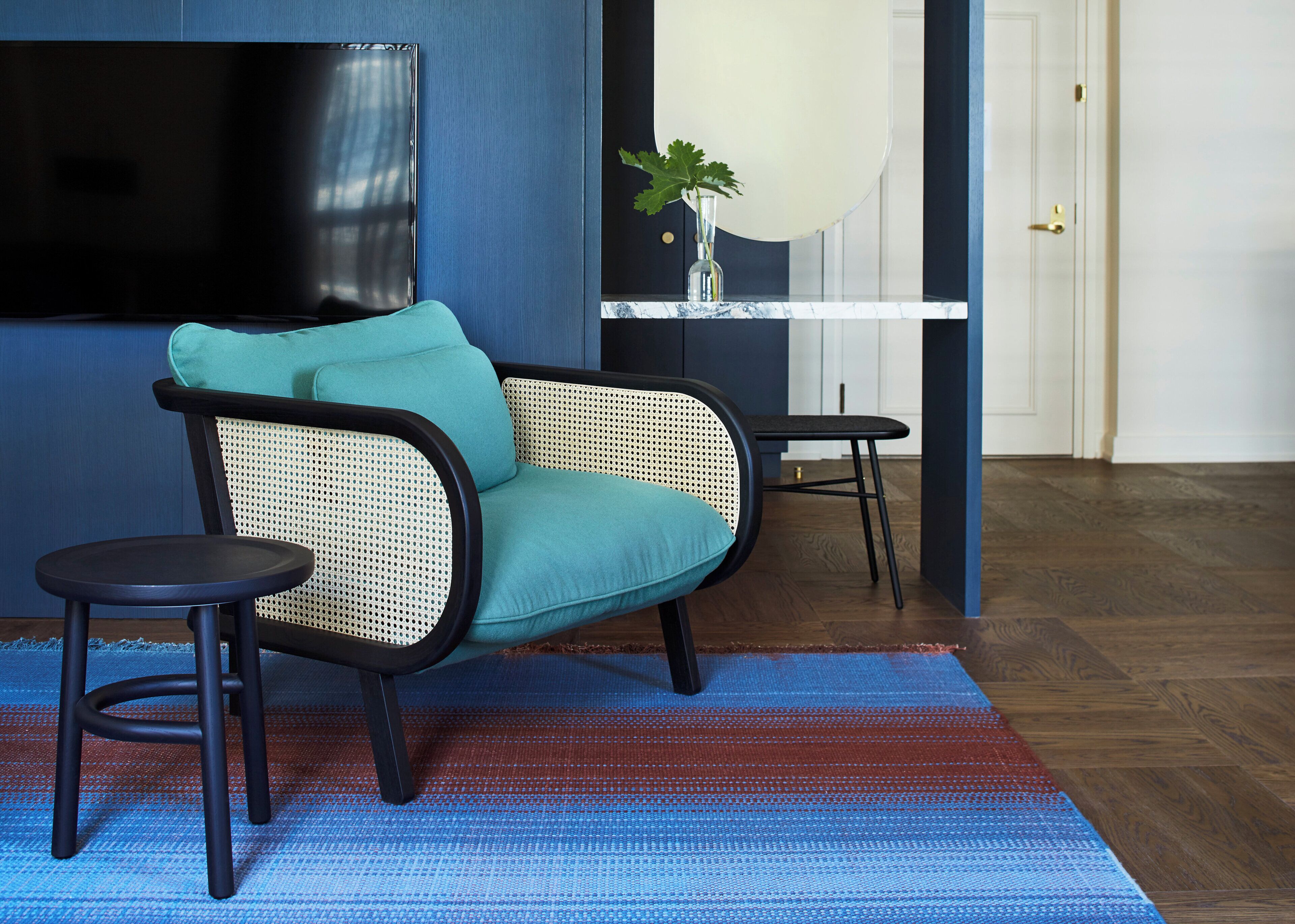 A modern living room with a sofa, a small table, and a TV mounted on the wall.
