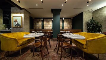 A library with yellow sofas, round tables, and bookshelves.