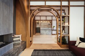 Een modern interieur met een houten boog die leidt naar een ruimte met een marmeren vloer en uitzicht op een bergachtig landschap.