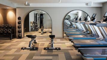 Un gimnasio con cintas de correr, máquinas de pesas y kettelbells.