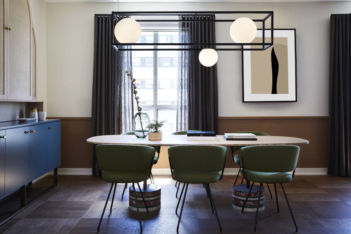 A modern dining area with a round table, green upholstered chairs, and a minimalist decor.