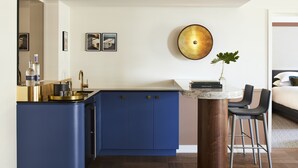 A modern kitchen with blue cabinets, a marble countertop, and a gold-colored wall decoration. - Kimpton Saint George by IHG (Toronto)