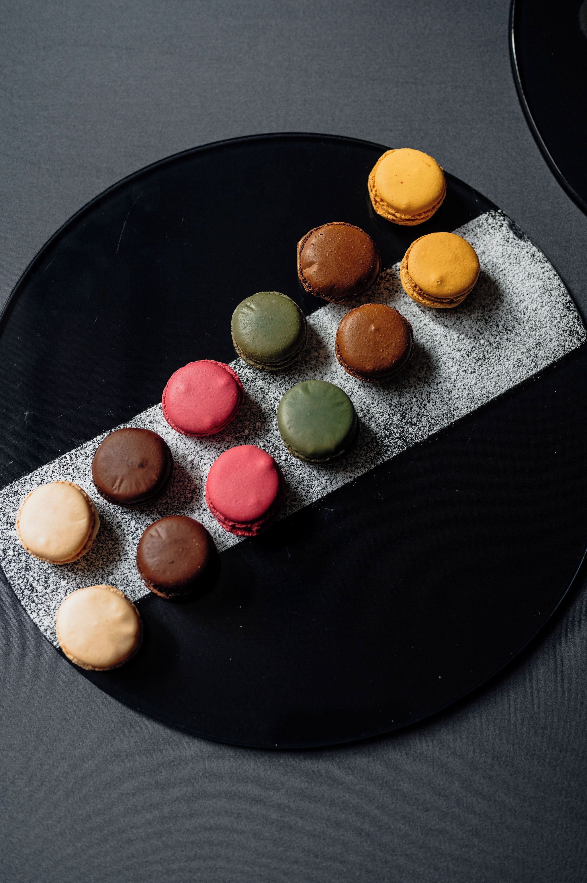 A black plate with macarons arranged in a line.
