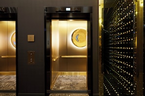 An elevator with a digital display, a directory sign, and a wall with reflective lights.