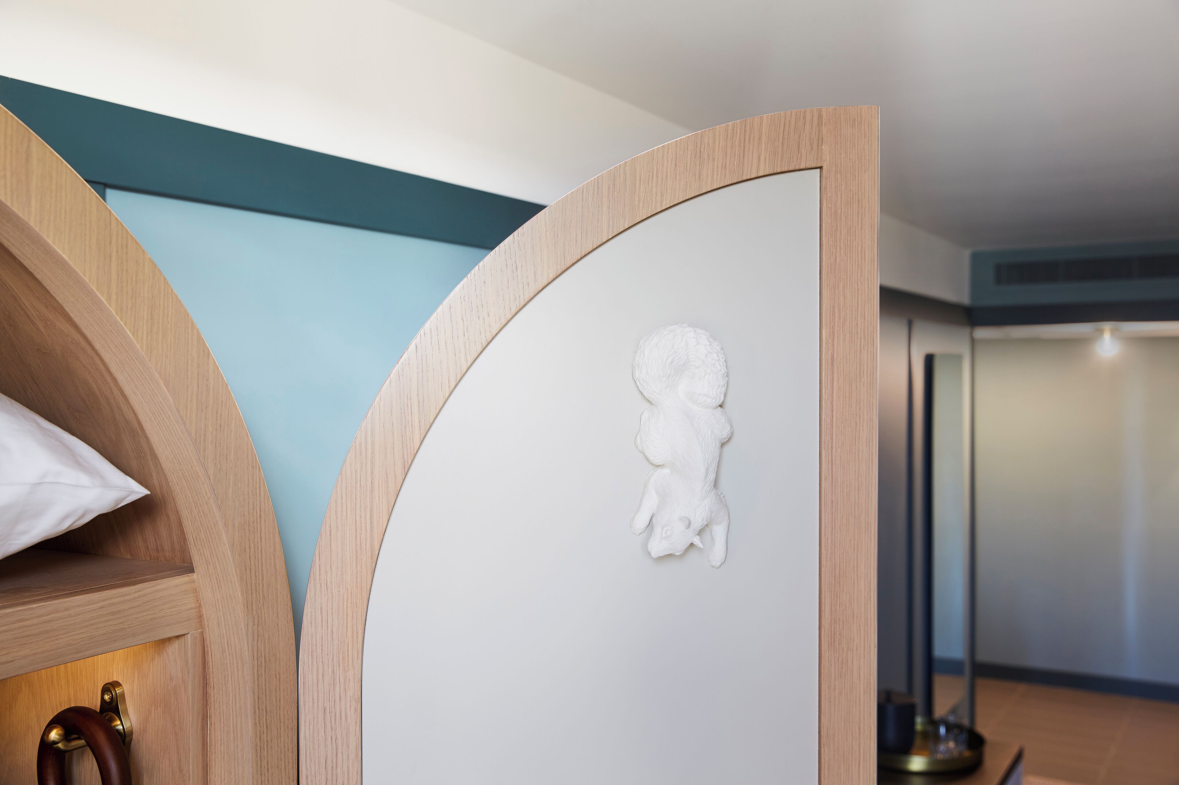 A modern room with a curved wooden partition, a white wall with a textured relief, and a floor lamp.
