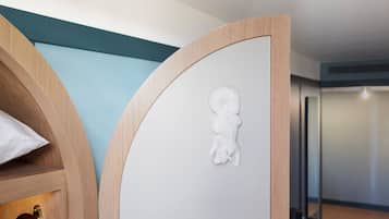 A modern room with a curved wooden partition, a white wall with a textured relief, and a floor lamp.