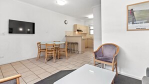 A compact living space with a dining area, kitchenette, and a TV mounted on the wall. - Taft Motor Inn (Glenelg)