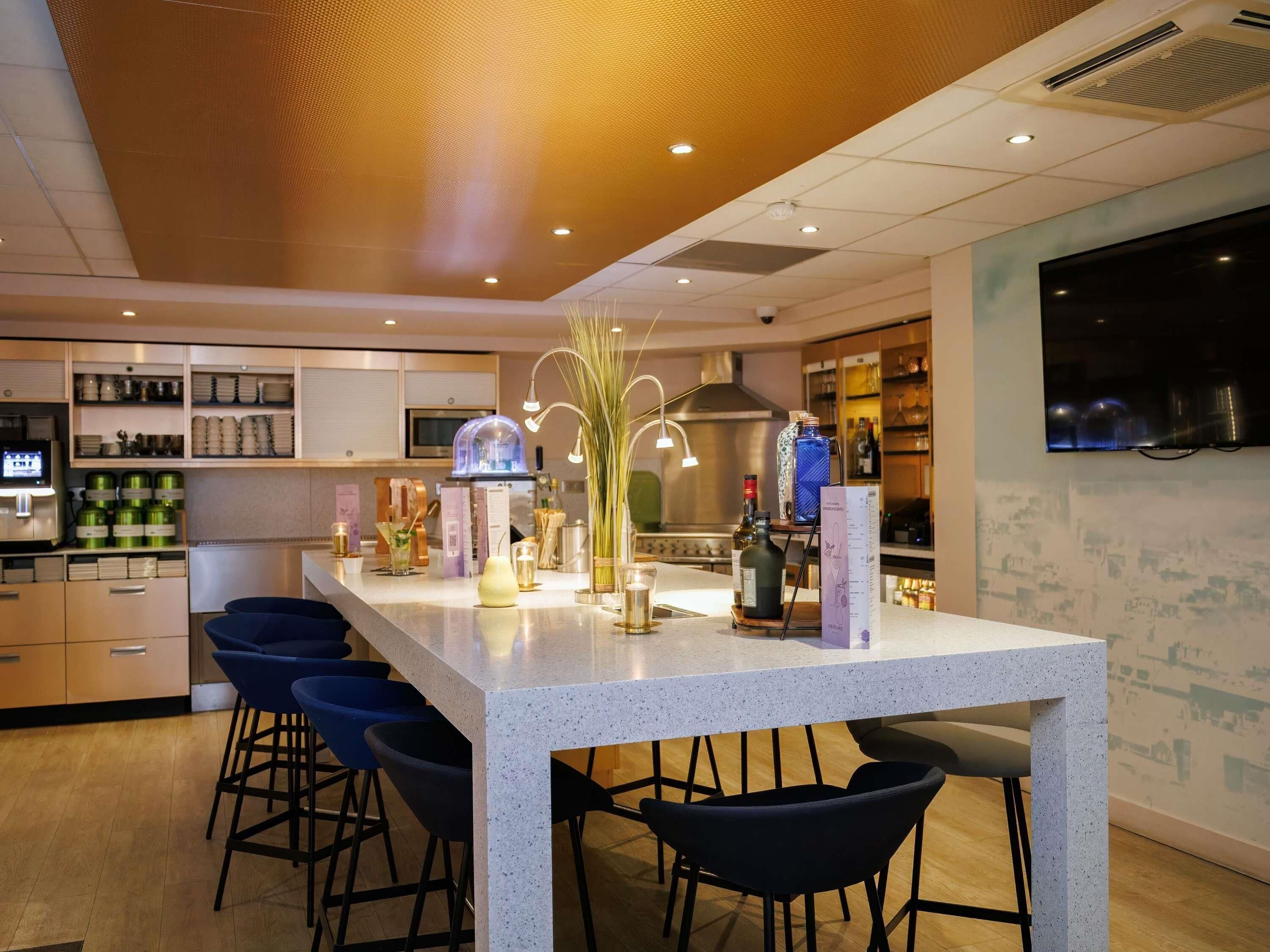 Een moderne keuken met een centraal eiland, barkrukken en een flatscreen televisie aan de muur.