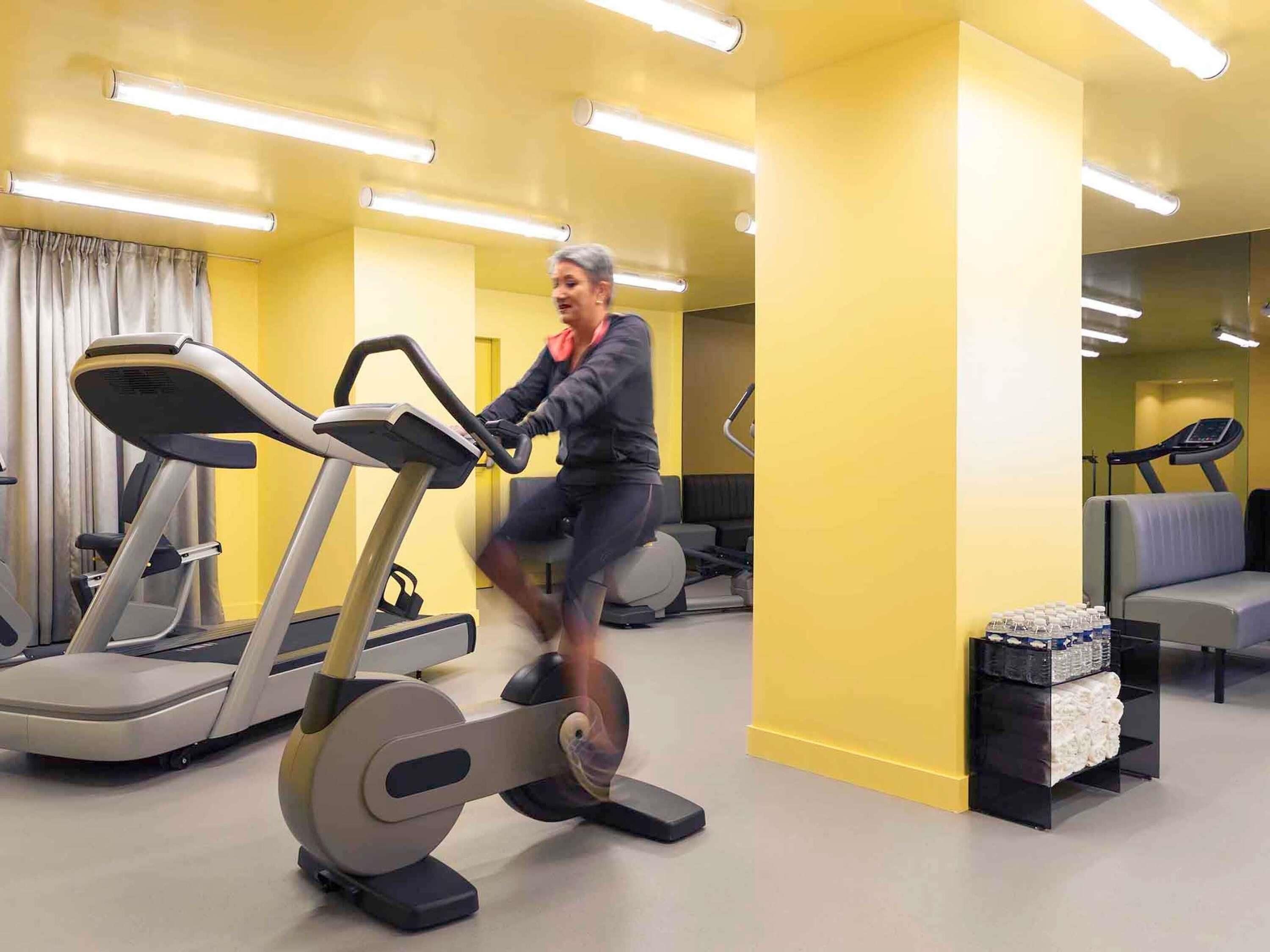 A gym with exercise equipment, a treadmill, and a mirrored wall.