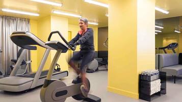 A gym with exercise equipment, a treadmill, and a mirrored wall.
