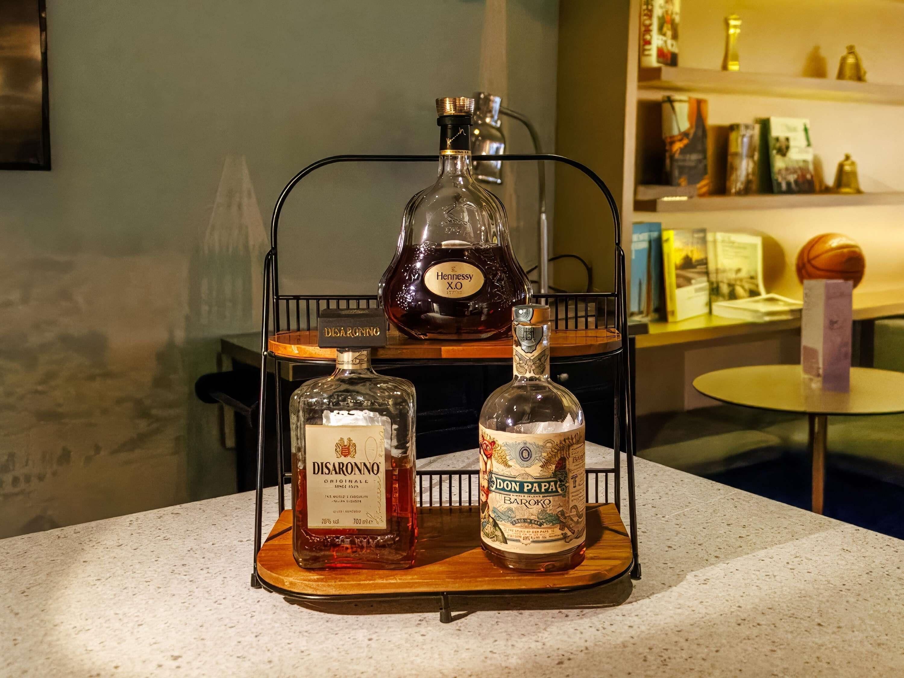 A bar area with three bottles of liquor on a metal rack.