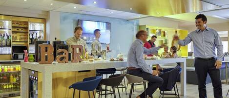 A modern bar area with stools, a counter with bar tools, and a visible TV screen.
