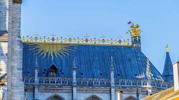 A historic building with a large blue roof, golden statues, and a flag.