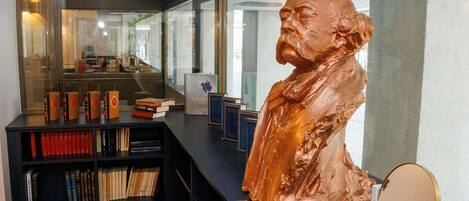 A modern interior with a large bronze bust, bookshelves, and a reflective surface.