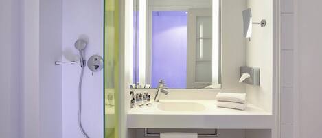 A modern bathroom with a glass shower enclosure, a white sink, and a large mirror.