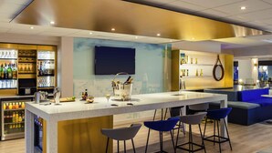 Uma área de bar moderna com balcão, banquetas e uma grande tela.