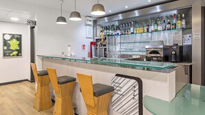 Un espace bar doté d’un comptoir en verre, de tabourets de bar et d’une variété de bouteilles d’alcool.