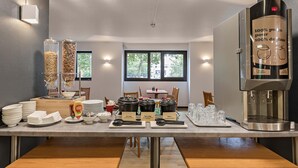 Un comptoir pour le petit-déjeuner, avec des machines à café, des bols et des condiments.