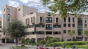 Un bâtiment moderne avec une enseigne indiquant « chambre d’hôtes », de nombreuses fenêtres et un espace de stationnement pour vélos.